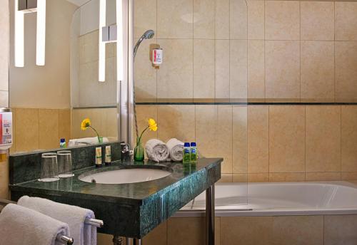 a bathroom with a sink and a bath tub at Come Inn Berlin Kurfürstendamm in Berlin