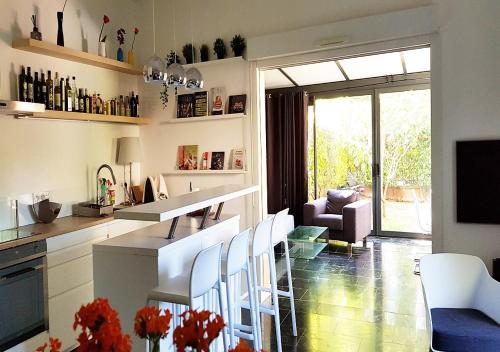 a kitchen with a table and chairs and a living room at Appartement contemporain jardin & jacuzzi in Voisins-le-Bretonneux