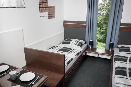 a bedroom with a bed and a table and a window at Triumph Inn Pension in Rangsdorf
