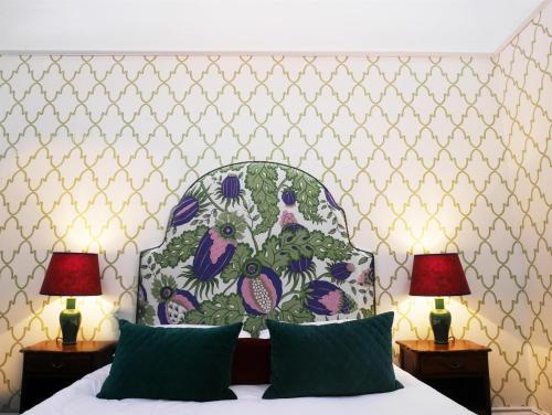 a bedroom with a bed with a floral headboard and two lamps at The Fleece in Witney