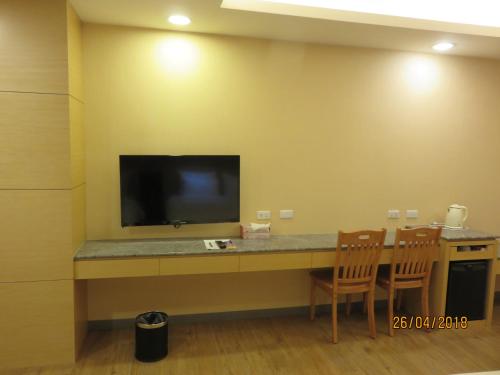 a room with a desk with a television and chairs at Mao Hua Motel in Dajia