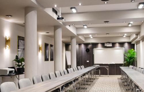 a lecture hall with rows of chairs and a white screen at Hotel Atrium in Kraków