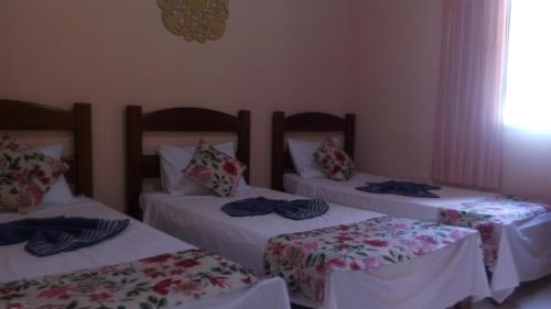 a room with three beds with blankets and pillows at Pousada Licuri in Serra do Cipo