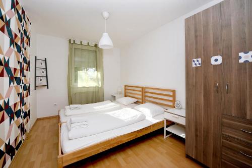 ペーチにあるiHome Apartment 5.0の白いベッド2台と木製キャビネット付きのベッドルーム1室が備わります。