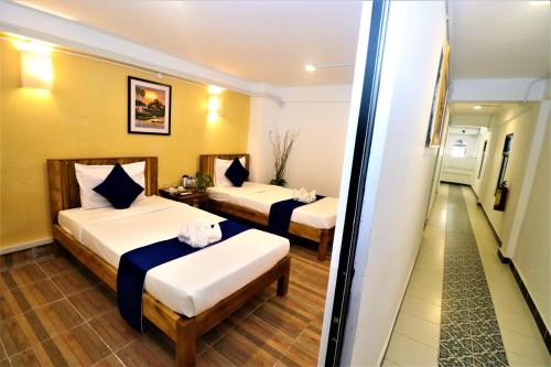 a hotel room with two beds and a hallway at Grand Elevation Hotel in Phnom Penh