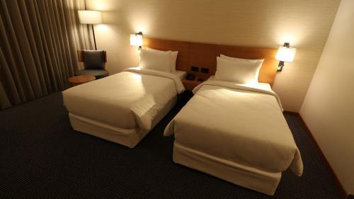 a hotel room with two beds and a chair at The Vern at BLVD in Nashik
