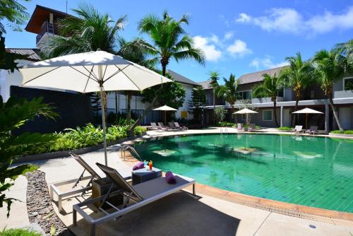 a pool at a resort with chairs and an umbrella at Twin Lotus Resort and Spa - SHA Plus - Adult Only "November - April" in Ko Lanta