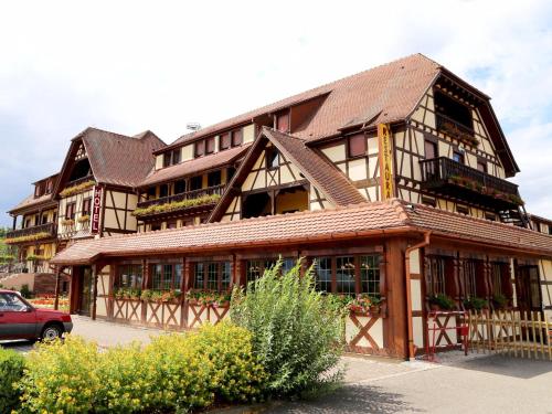 a large wooden building with a car parked in front of it at Hotel Restaurant Au Parc des Cigognes in Kintzheim