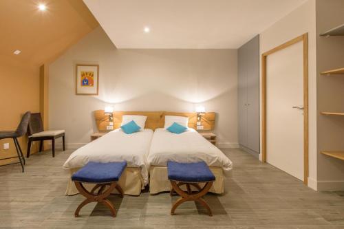 een slaapkamer met een bed en twee blauwe stoelen bij Casa Mir in Saint-Lary-Soulan