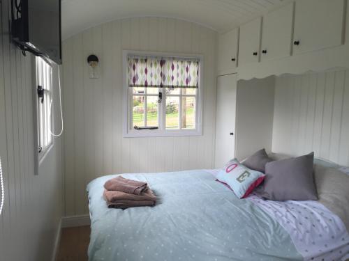 a bedroom with a bed with towels on it at Weatherhead Farm Shepherds Hut in Buckingham