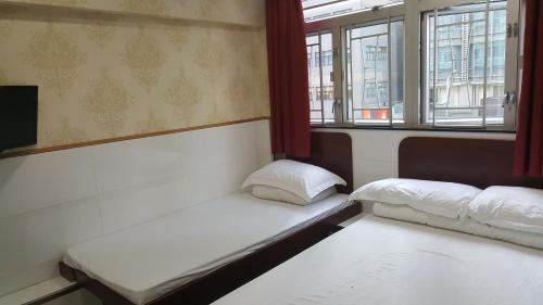 2 Betten in einem Zimmer mit Fenstern in der Unterkunft Lung Wa Hotel in Hongkong
