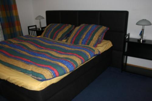 Una cama con una manta de rayas de colores. en Ferienwohnung Bücker en Telgte
