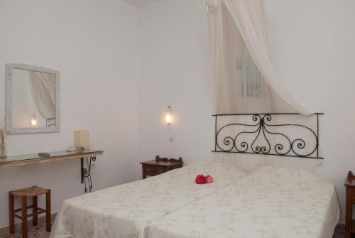 a bedroom with a white bed with a red flower on it at Andriani's Guest House in Mýkonos City