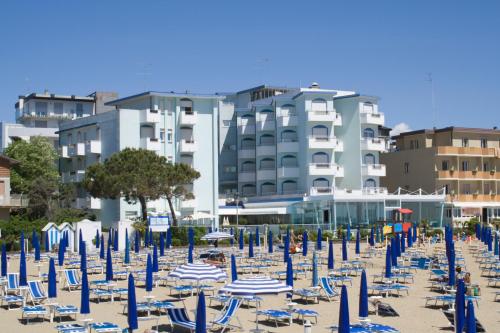 een strand gevuld met blauwe en witte stoelen en parasols bij Hotel Niagara in Lido di Jesolo