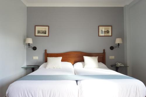 two beds in a bedroom with white walls and lamps at Villa Soledad in Torrejón de Ardoz