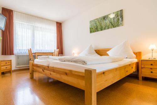 a bedroom with a wooden bed with white sheets at Gasthaus Pension Löwen in Freiburg im Breisgau