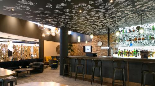 a bar in a restaurant with a ceiling decorated with flowers at Mercure Bordeaux Aéroport in Mérignac