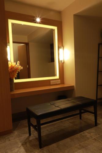 a mirror in a room with a bench in front of it at The Vern at BLVD in Nashik