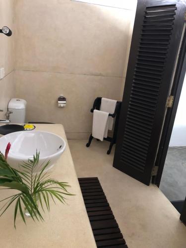 a bathroom with a white sink and a plant at Galle Henna Beach House in Unawatuna
