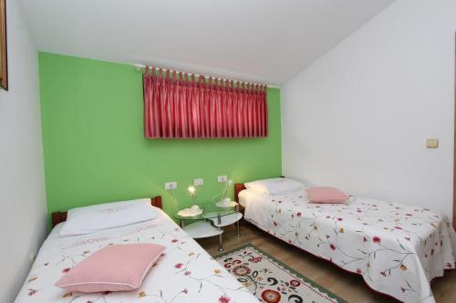 Habitación con 2 camas y pared verde. en Apartments Daria, en Rovinj