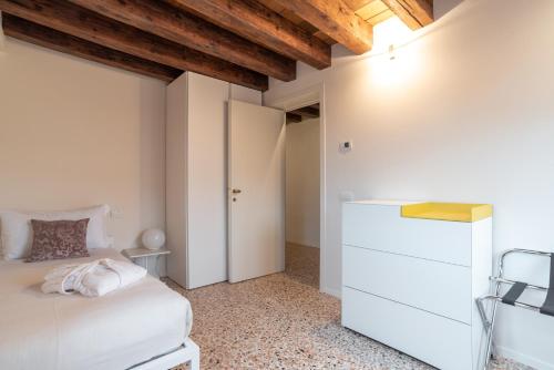 a bedroom with a white bed and a white cabinet at Palazzo Vendramin Costa in Venice