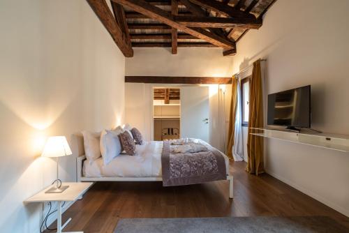 a bedroom with a bed and a television and a table at Palazzo Vendramin Costa in Venice