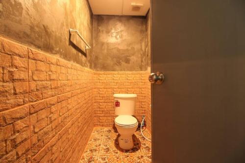 uma casa de banho com um WC numa parede de tijolos em Falik Farm Stay em Phra Nakhon Si Ayutthaya