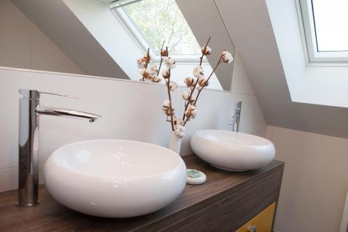 un bagno con due lavandini e un vaso con fiori di Maison d hotes Coeur de Village Alsace & spa a Rohrwiller