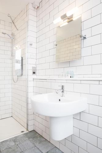 a white bathroom with a sink and a mirror at The Lerryn in Falmouth