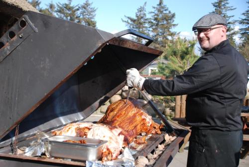 a man is cooking a turkey on a grill at Hytteby – Hanstholm Camping – Thy Feriepark in Hanstholm