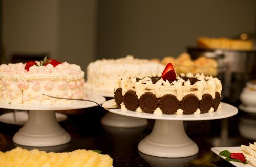 a group of cakes on plates on a table at Alven Hotel by Slaviero Hotéis in Joinville