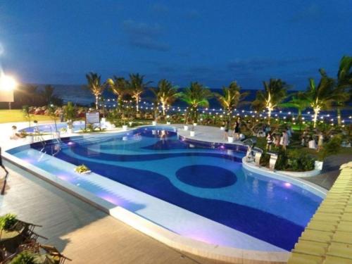 a swimming pool at night with the ocean in the background at Flat Summer House em Guarajuba in Guarajuba