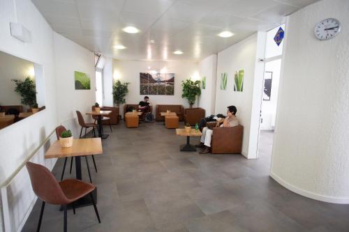 una hall con persone sedute su sedie e tavoli di City Hostel Geneva a Ginevra