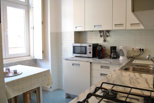リスボンにあるChiado 2 Bedroom Elegant Apartmentの白いキャビネット、シンク、電子レンジ付きのキッチンが備わります。