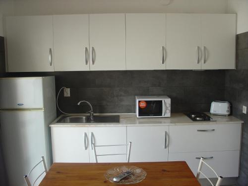 a kitchen with white cabinets and a sink and a table at Apartamentos Central in Quarteira