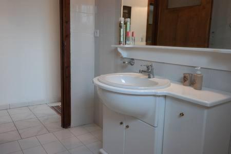 a white bathroom with a sink and a mirror at Oasis of CalmnessΕ in Ardánion