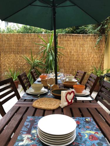 a wooden table with plates and an umbrella at BS VILLAS RC PORTO in Porto