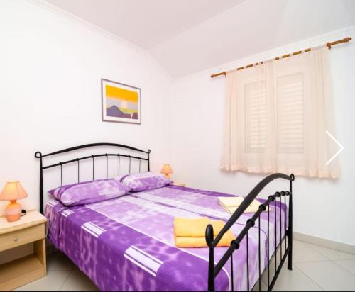 - une chambre avec un lit doté de draps violets et une fenêtre dans l'établissement Apartments Baltazar, à Dubrovnik