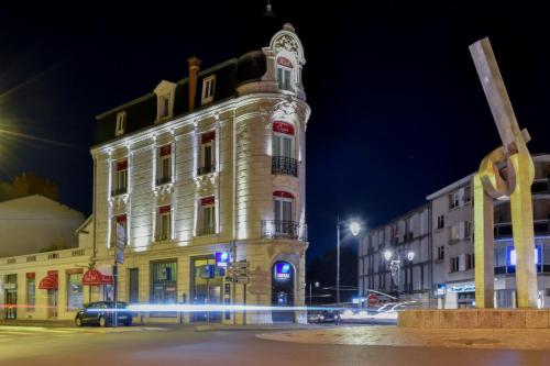 a building with a clock tower at night at Élysée Hôtel in Châteauroux