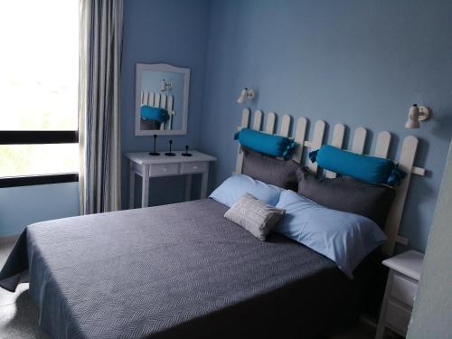 a bedroom with a bed with blue walls and a window at Apartamento LE SOLEIL Complex Amaya Fuerteventura in Costa de Antigua