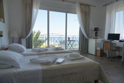 two beds in a room with a large window at Akrotiri Hotel in Chania