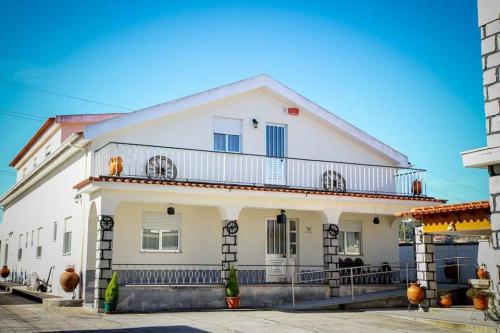 a white house with a balcony on a street at Hospedaria Santa Cruz in Seia