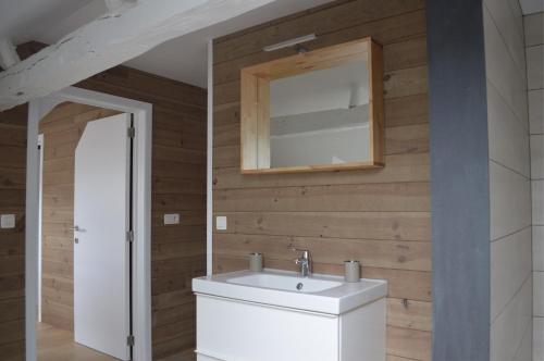 een badkamer met een witte wastafel en een spiegel bij la tourelle d’Achille leontine in Rochefort