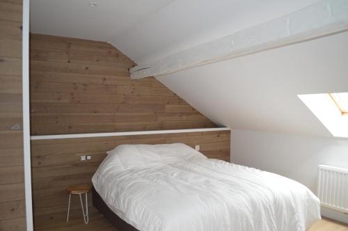 1 dormitorio con cama blanca y paredes de madera en la tourelle d’Achille leontine, en Rochefort