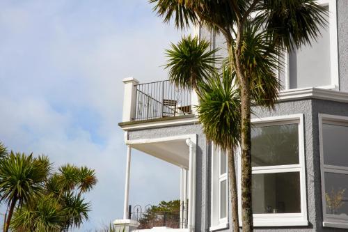 a house with a balcony and palm trees at The Lerryn in Falmouth