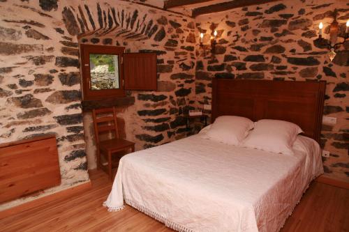 1 dormitorio con 1 cama en una habitación de piedra en Casa Rural Pikatzaenea, en Sopuerta