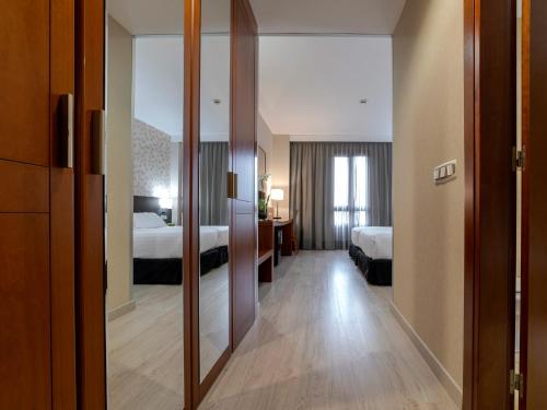 a hotel room with two beds and a mirror at Hotel Plaza Las Matas in Las Rozas de Madrid