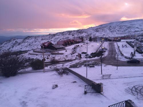 a snow covered hill with a road and a mountain at Alojamento de montanha in Penhas da Saúde