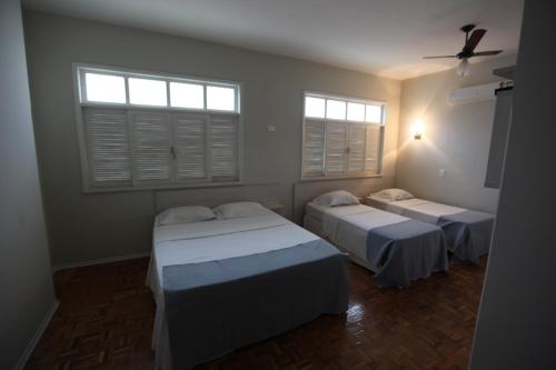 two beds in a room with two windows at HOTEL ALVORADA in Leopoldina