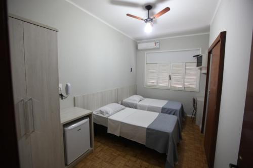 Habitación pequeña con 2 camas y ventilador de techo. en HOTEL ALVORADA, en Leopoldina